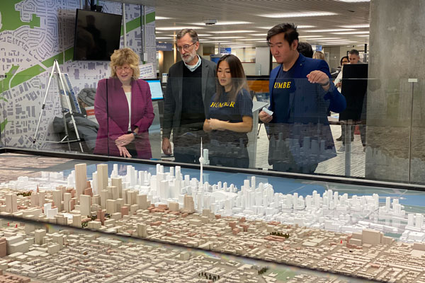 group of people looking at scale model of Toronto underneath glass case