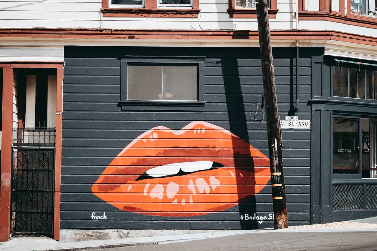 Red and orange lips painted on the side of a black building.