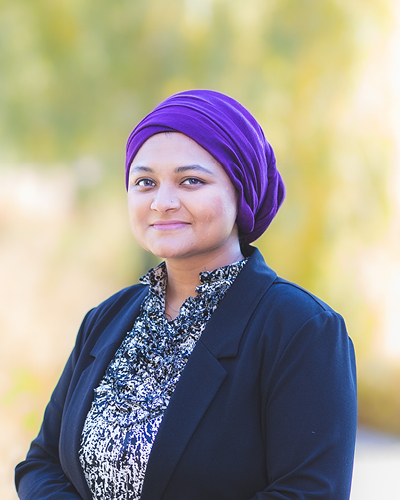 Sana Mahmood Executive Assistant, Office of the Senior Vice-President, Academic, smiles while wearing a navy blue blazer and a blue and white shirt. 