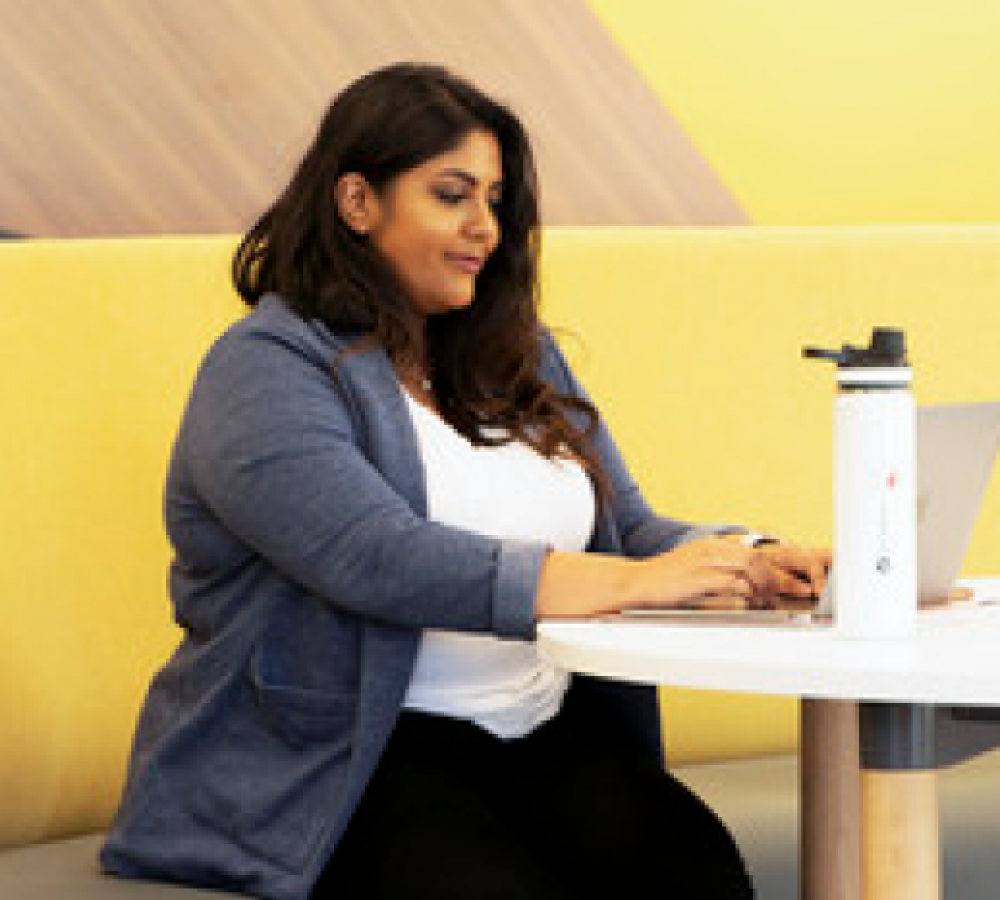 Humber student sitting at a table with her laptop and water bottle