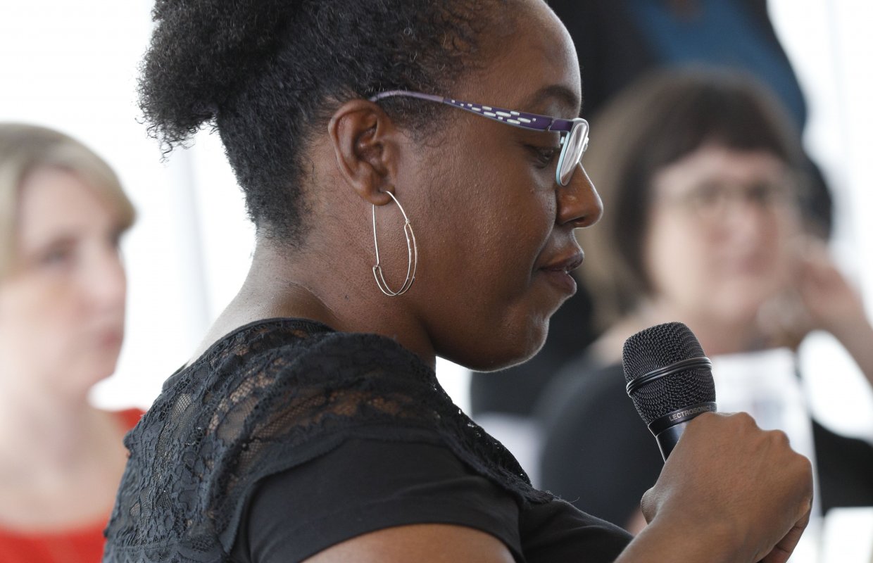 Black woman in a classroom holding a microphone in her hand.