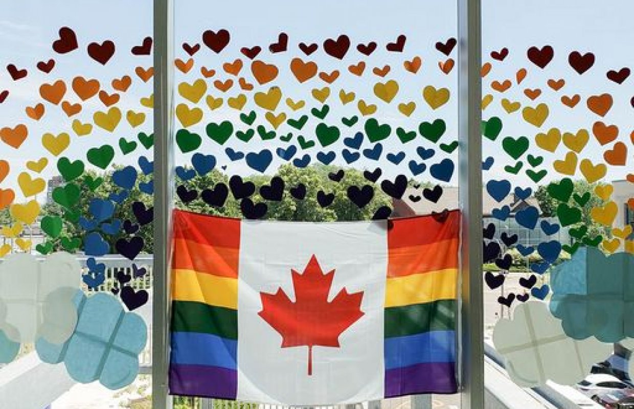Rainbow Candian Flag in a window with multicoloured hearts around it