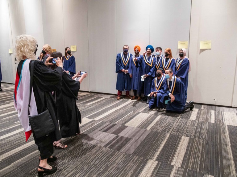 People using cell phones to take photos of a group of graduates