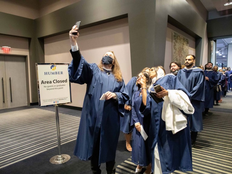 A graduate at the front of the line taking a selfie