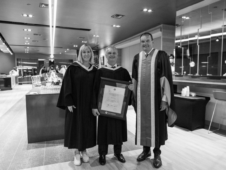 Two Humber faculty posing with former Humber president Chris Whitaker