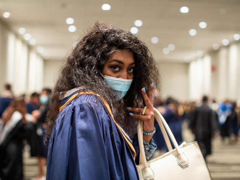 Humber graduate holding a purse and making a peace sign