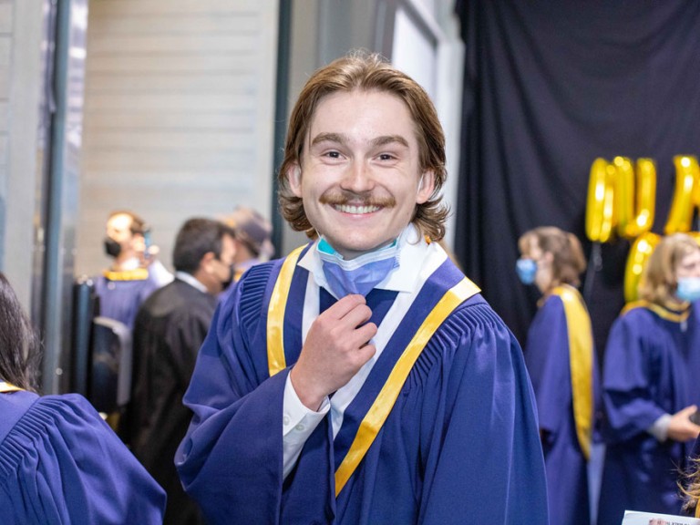 Humber graduate pulling down their face mask and smiling