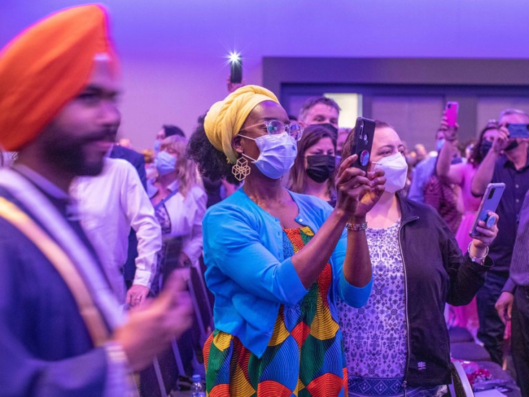 Ceremony guests wearing face masks take cell phone photos