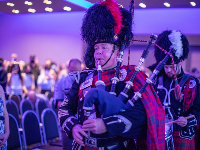 Person in Scottish formalwear playing the bagpipes