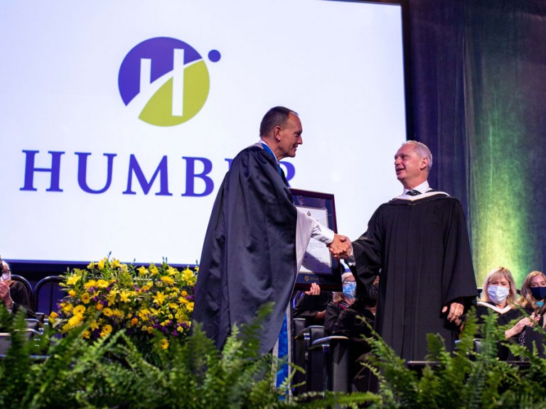 A person shaking hands with former Humber president Chris Whitaker