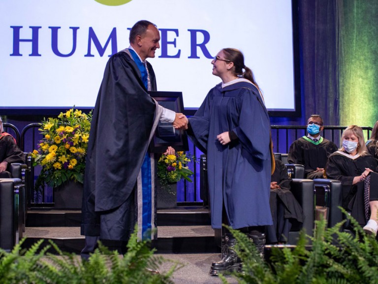 Chris Whitaker shaking hands with a graduate