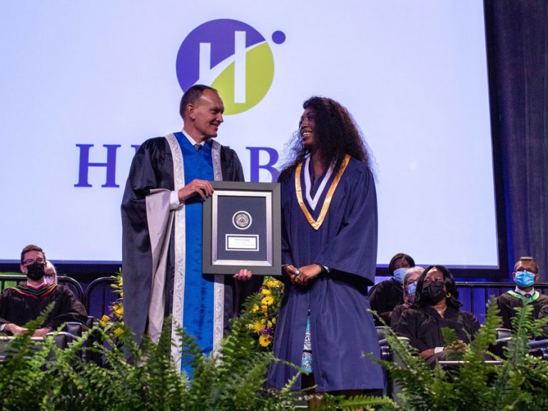 Former Humber president Chris Whitaker on stage with a graduate
