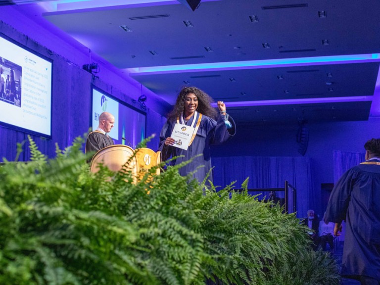 Graduate crossing the stage holding up a fist