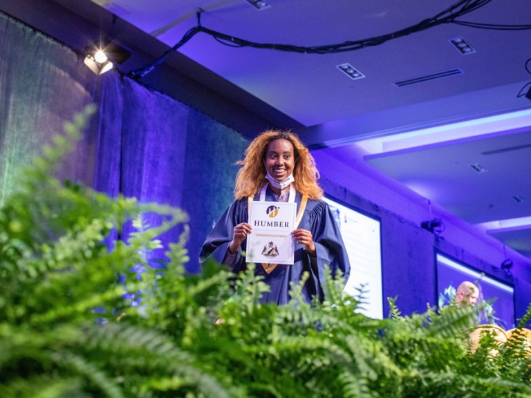 Graduate smiling exiting the stage with their diploma