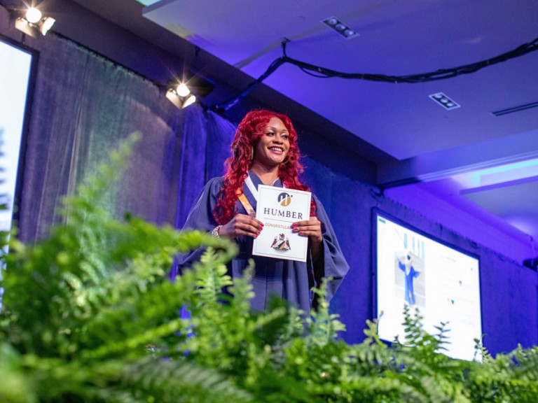 Graduate smiling facing the audience with their certificate