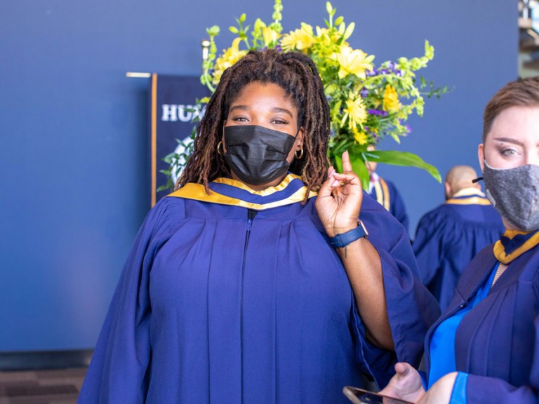 Humber graduate wearing a face mask making a peace sign