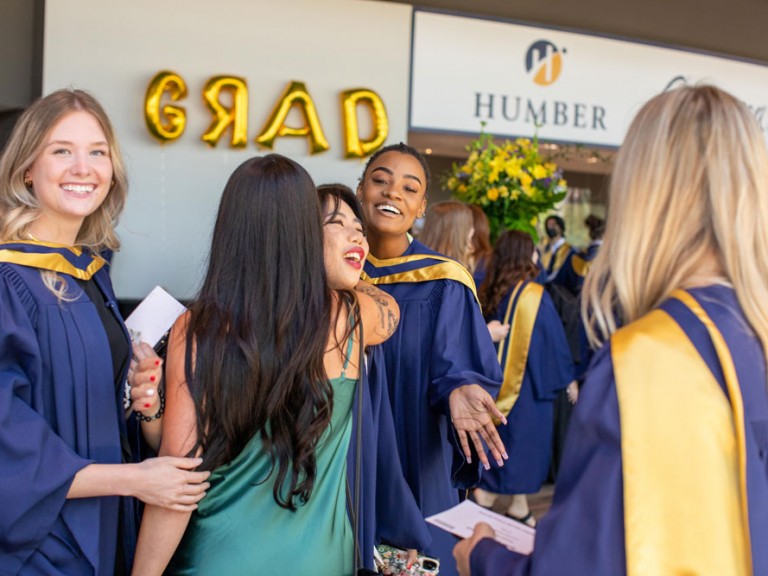 Two people hugging among a group of Humber graduates