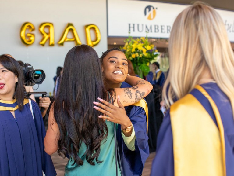 Graduate hugging another person and smiling