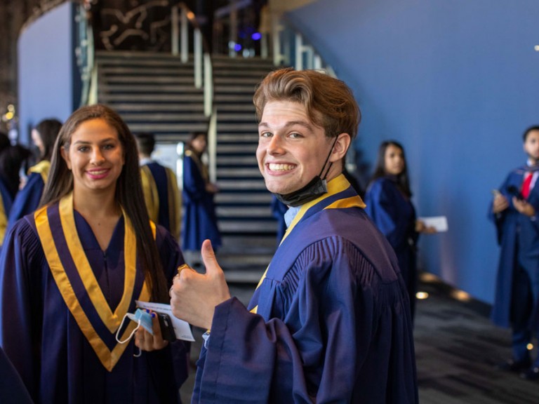 Graduate smiling and making a thumbs up gesture