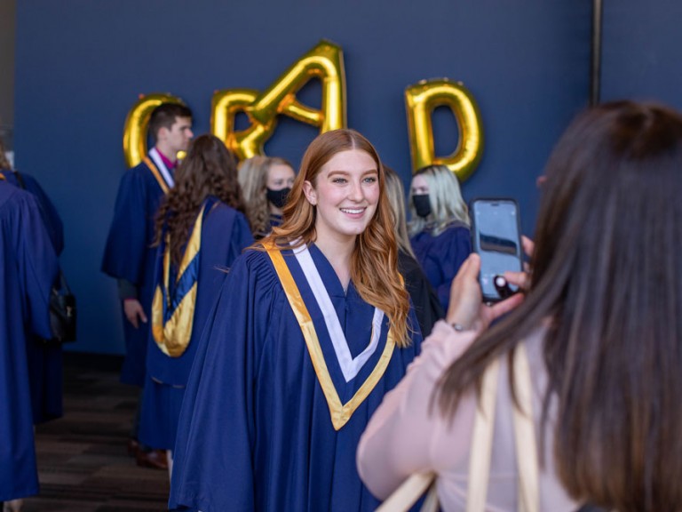 A ceremony attendee taking a cell phone photo of a Humber graduate