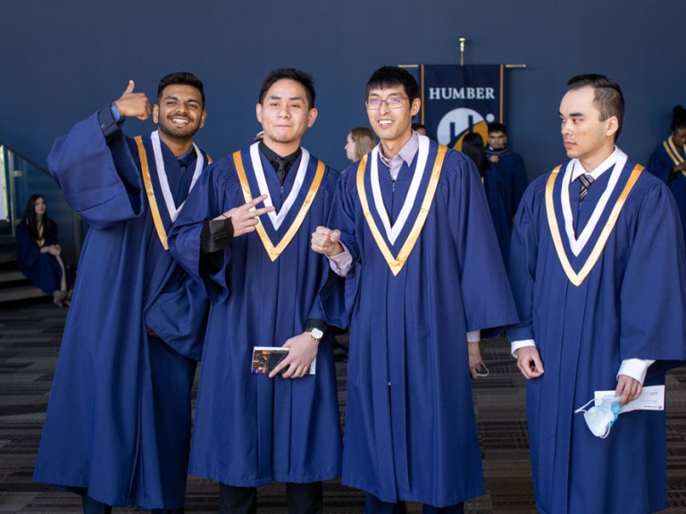 Group of four graduates posing and gesturing