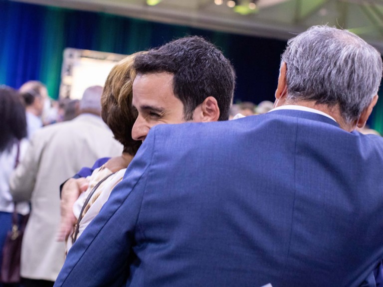 Humber graduate hugging two people