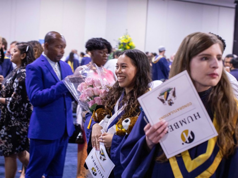 Graduate holding flowers and smiling