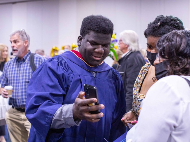 Graduate showing their phone to guests