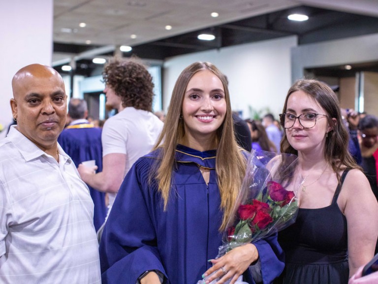Graduate holding roses with two people