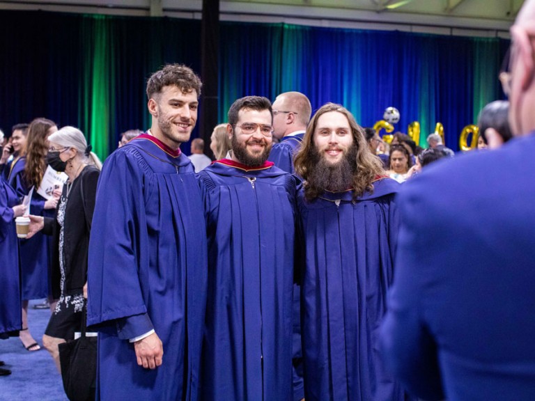 Three graduates posing for a photographer