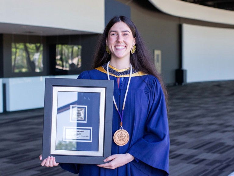 Smiling Humber Indigenous graduate holding their framed document