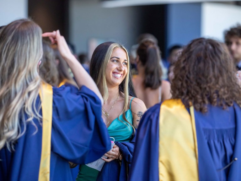 Graduate smiling and holding their gown over their arm