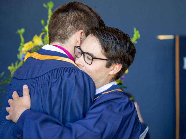 Two graduates hugging