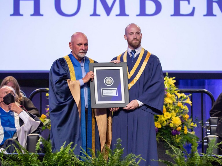 Two people holding up a framed document