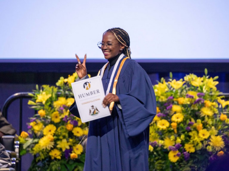 Graduate on stage making a peace sign