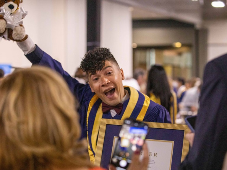 Graduate holding a teddy bear in the air