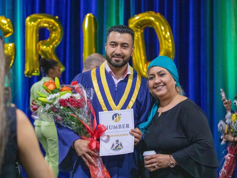 Graduate holding roses posing with a family member