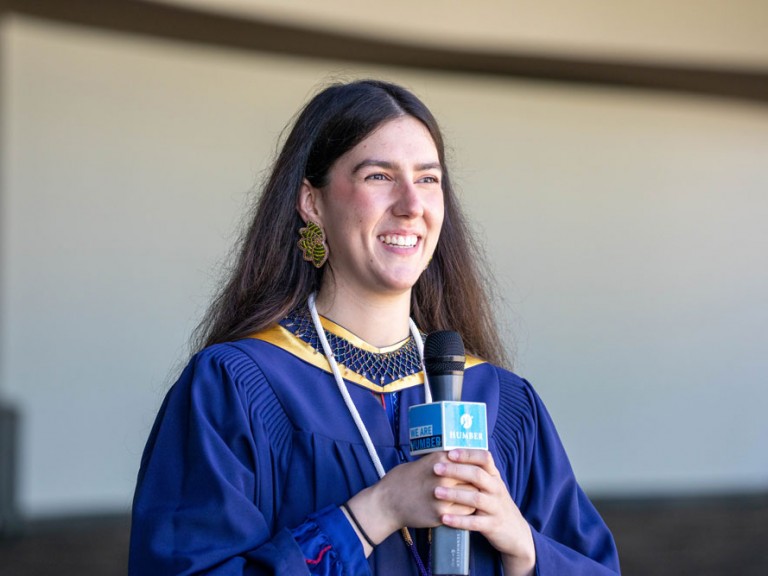 Indigenous graduate smiling with a micrphone