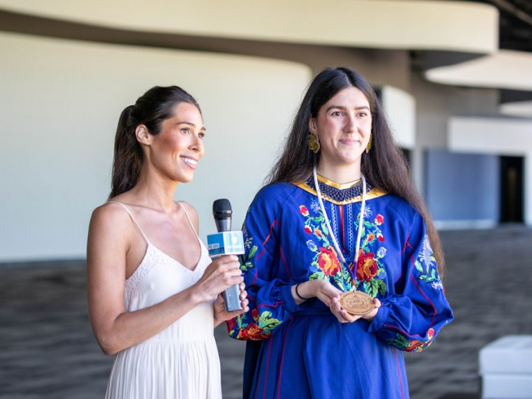 Person with a microphone standing next to Humber Indigenous graduate