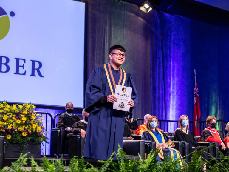 New Humber Graduate on stage showing Humber Diploma