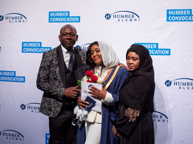 Humber graduate smiling at camera with parents