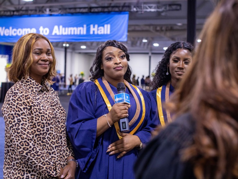 Graduate looking into camera and holding microphone