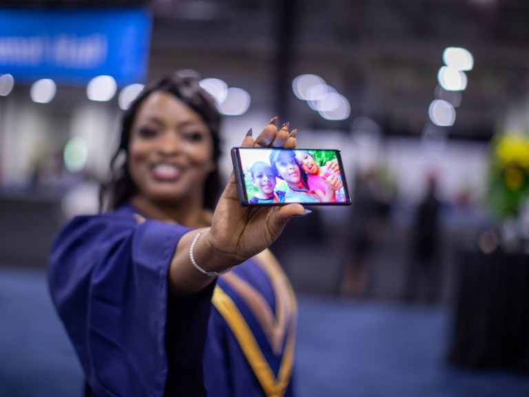Humber graduate showing off photo of children on cell phone