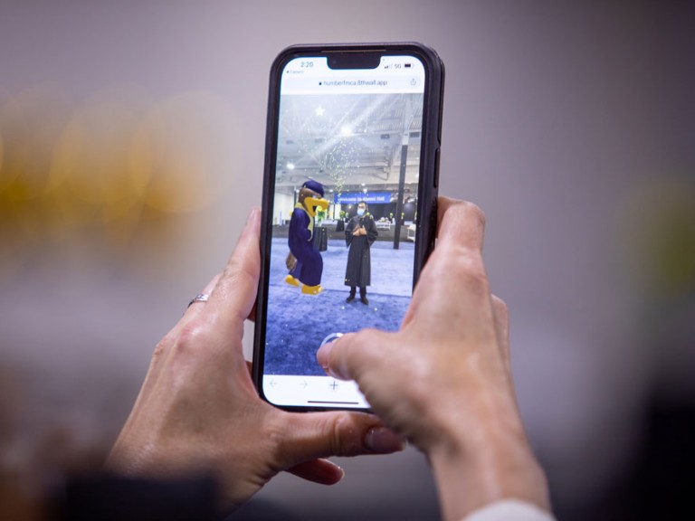 Phone taking picture of Humber Mascot with Graduate