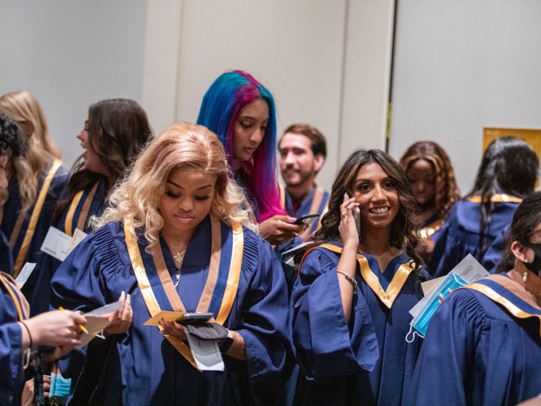 Graduates looking at phones and smiling
