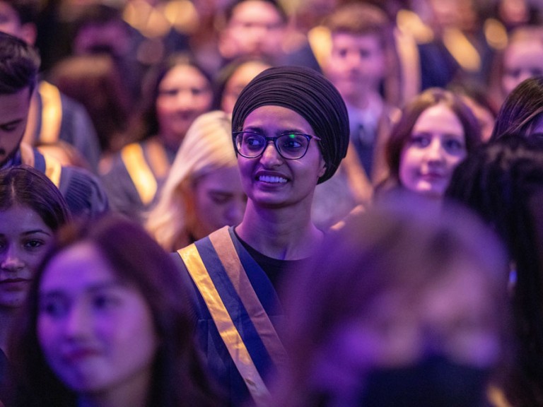 person smiling in graduation crowd