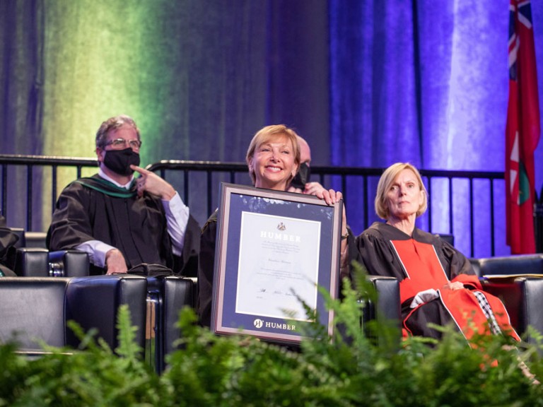 Person holding Humber Diploma and smiling