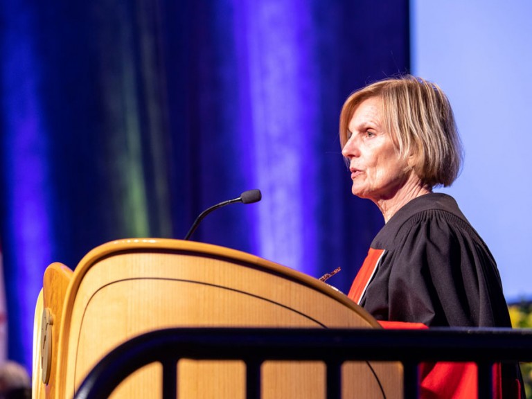 Speaker at Humber Graduation Podium wearing black and red regalia