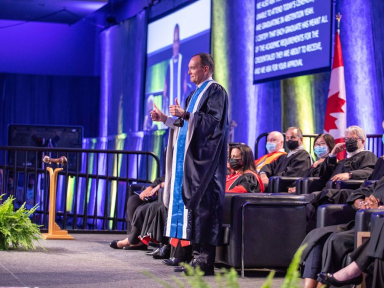 Former Humber College President Chris Whitaker holding up his thumbs and smiling on Graduation Stage