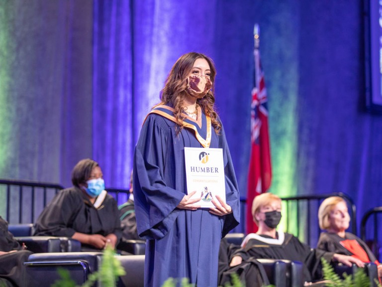 person on stage holding their Humber Diploma